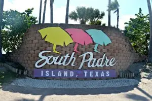 Colorful South Padre Island, Texas welcome sign surrounded by palm trees under a bright blue sky